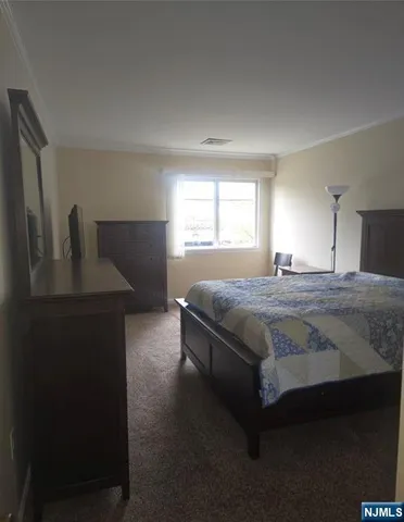 a bedroom with a bed and a dresser next to a window