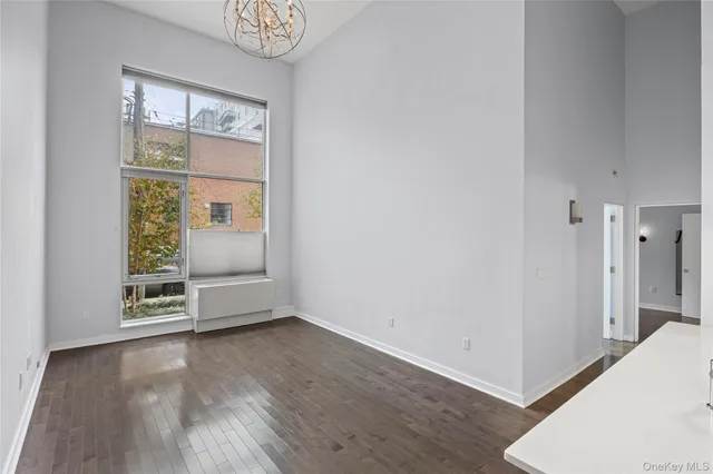 an empty room with wooden floor cabinet and windows