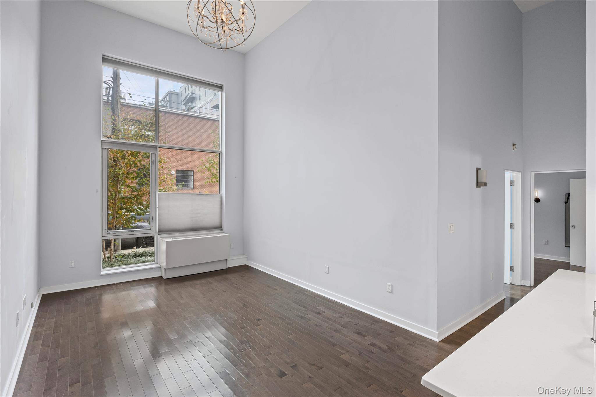240 51st Avenue, Unit 1H Queens, NY 11101 - Photo 22 of 39 an empty room with wooden floor cabinet and windows