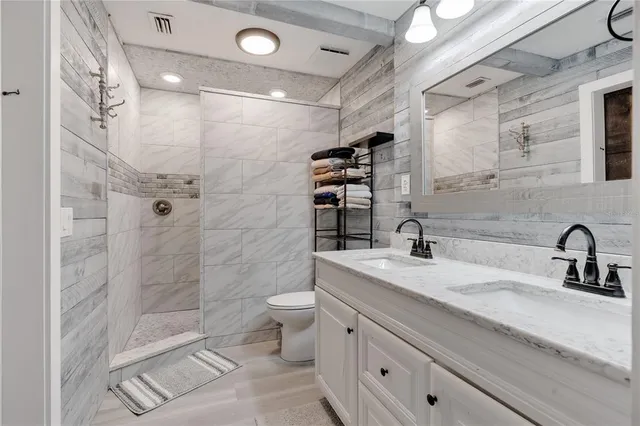 a bathroom with a granite countertop toilet a sink and a mirror