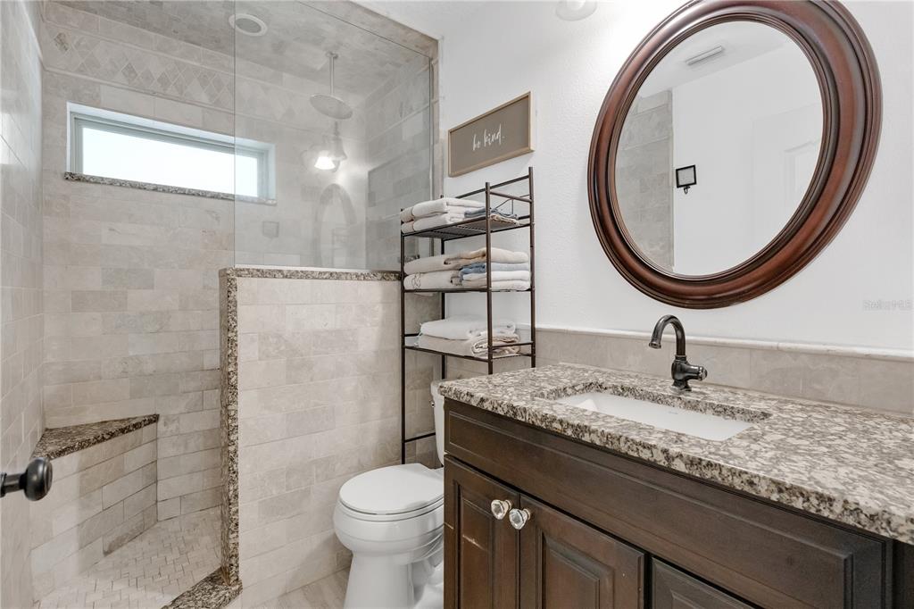 4410 Mildred Bass Road St. Cloud, FL 34772 - Photo 16 of 42 a bathroom with a granite countertop toilet a sink and a mirror