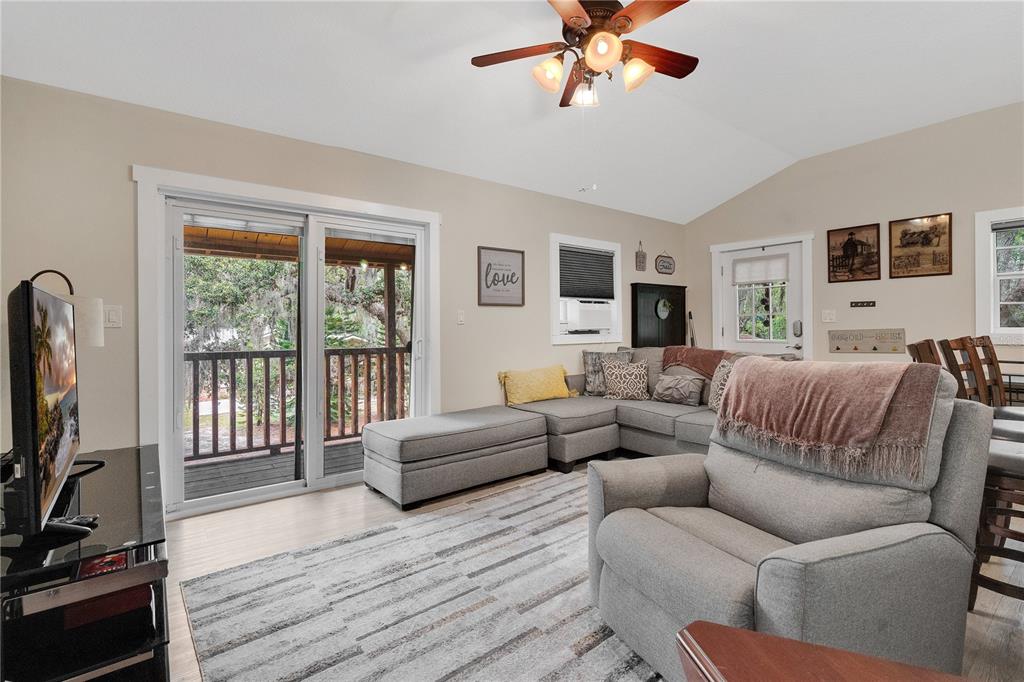 4410 Mildred Bass Road St. Cloud, FL 34772 - Photo 27 of 42 a living room with furniture a flat screen tv and a floor to ceiling window