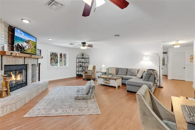a living room with furniture kitchen view and a wooden floor