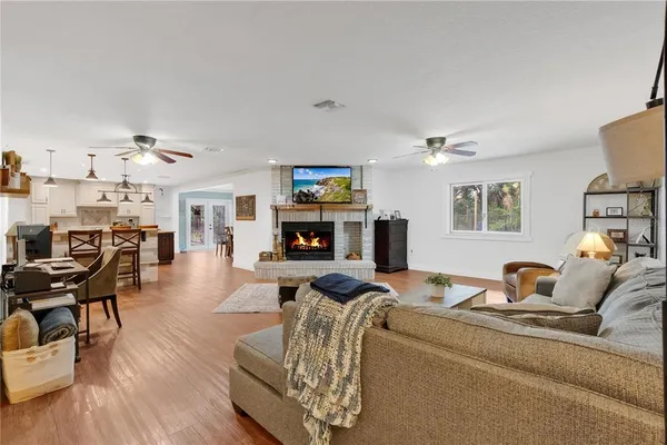 a living room with furniture kitchen view and a wooden floor