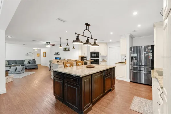 a kitchen with stainless steel appliances kitchen island a hardwood floor and a view of living room