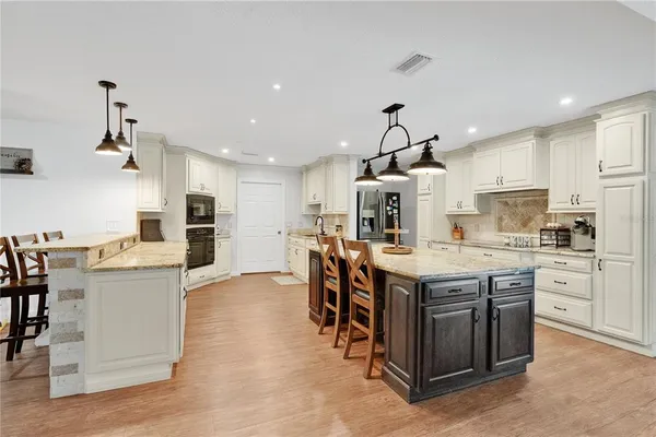 a kitchen with stainless steel appliances kitchen island granite countertop a table and chairs in it