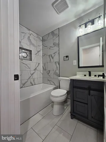 a bathroom with a toilet a sink a mirror a bathtub and vanity