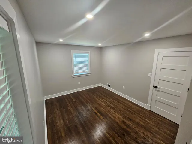 an empty room with wooden floor and window