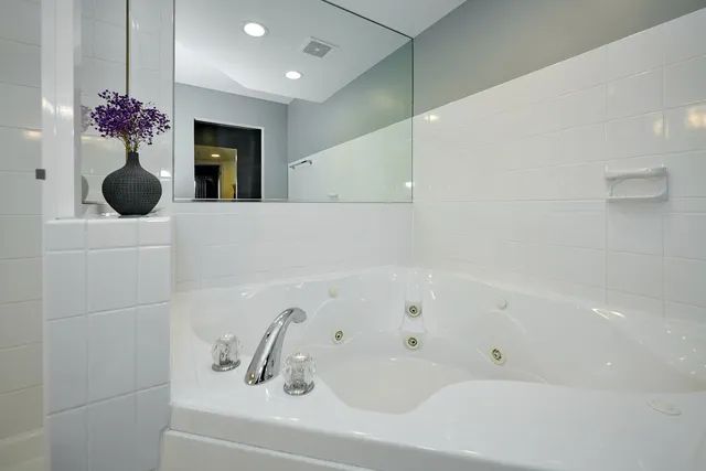 a bathroom with a tub a sink and mirror