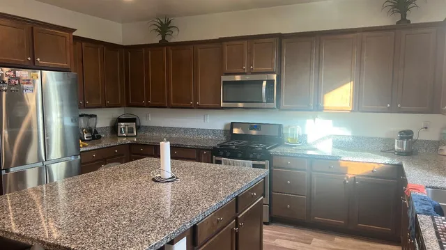 a kitchen with kitchen island granite countertop a sink stainless steel appliances and cabinets