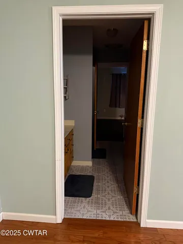 a view of a hallway with wooden floor and a living room