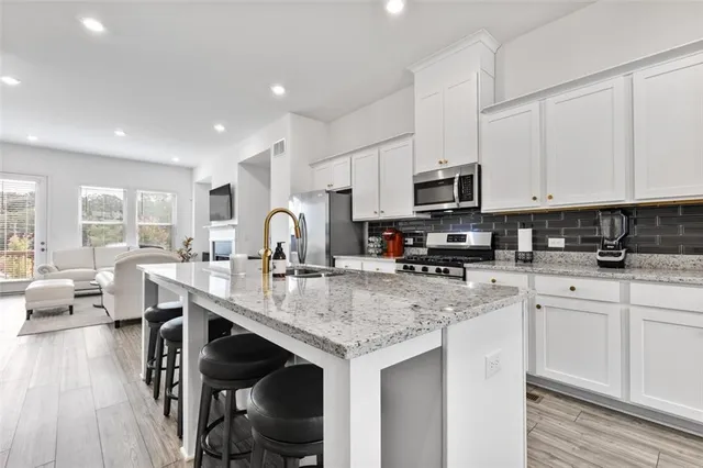 a kitchen with stainless steel appliances granite countertop a stove a sink and white cabinets