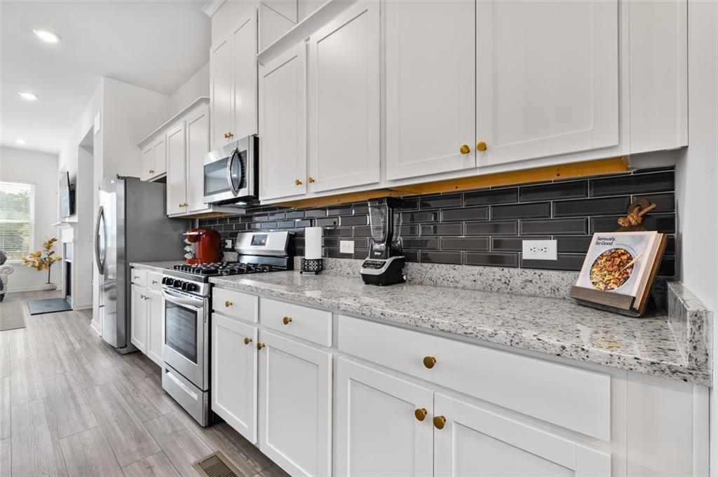 1182 Edwin Lane Sugar Hill, GA 30518 - Photo 7 of 32 a kitchen with stainless steel appliances granite countertop a stove a sink and white cabinets