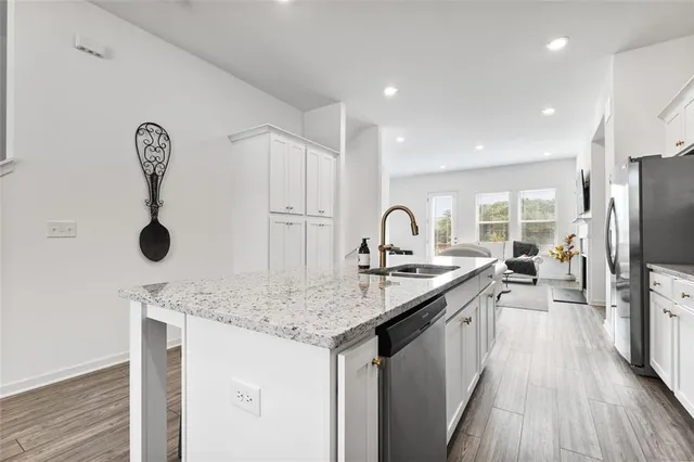 a kitchen with stainless steel appliances a refrigerator sink and white cabinets