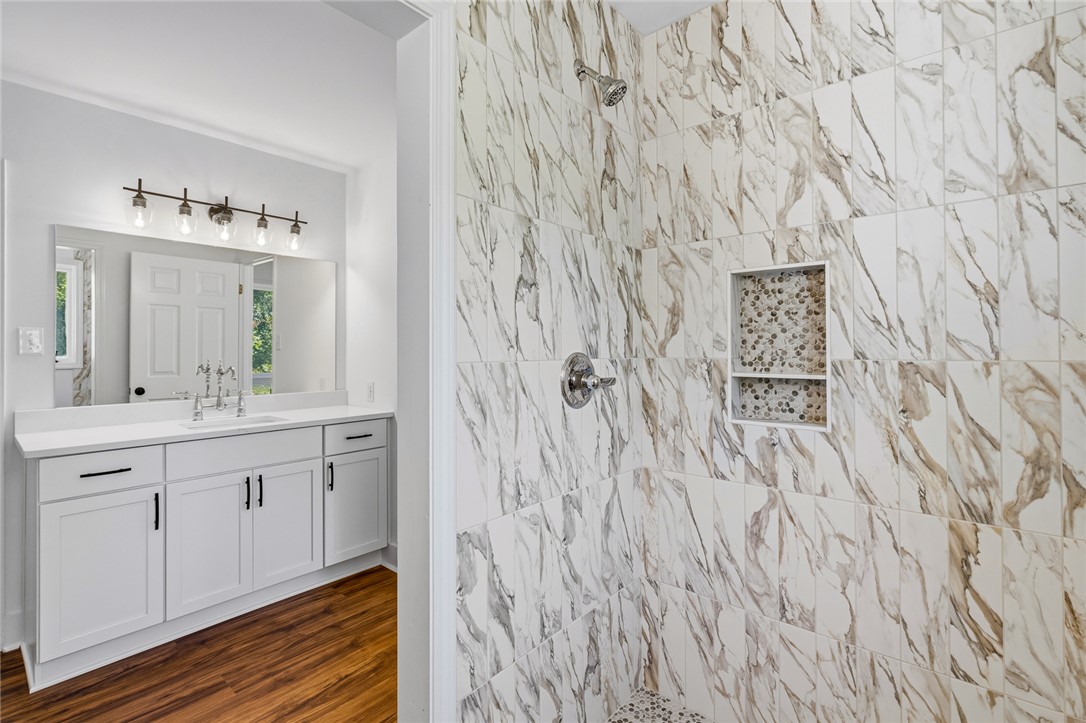 208 Williamsburg Road Anderson, SC 29621 - Photo 26 of 48 Elegantly veined shower tile coordinates beautifully with a clean white vanity and rich wood-toned flooring.