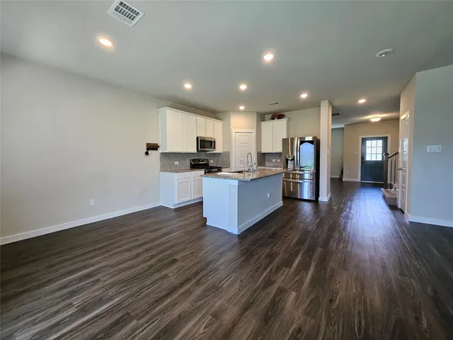 an open kitchen with wooden floor and stainless steel appliances