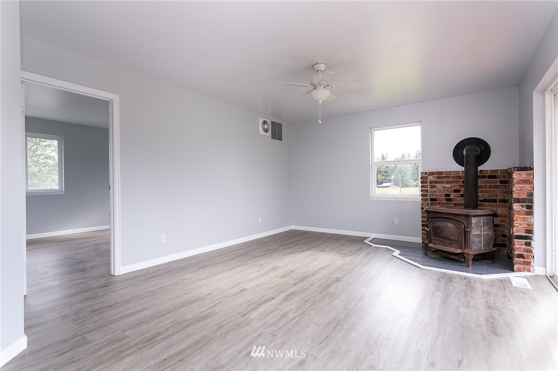 2419 East Badger Road Everson, WA 98247 - Photo 13 of 34 an empty room with wooden floor a ceiling fan and windows