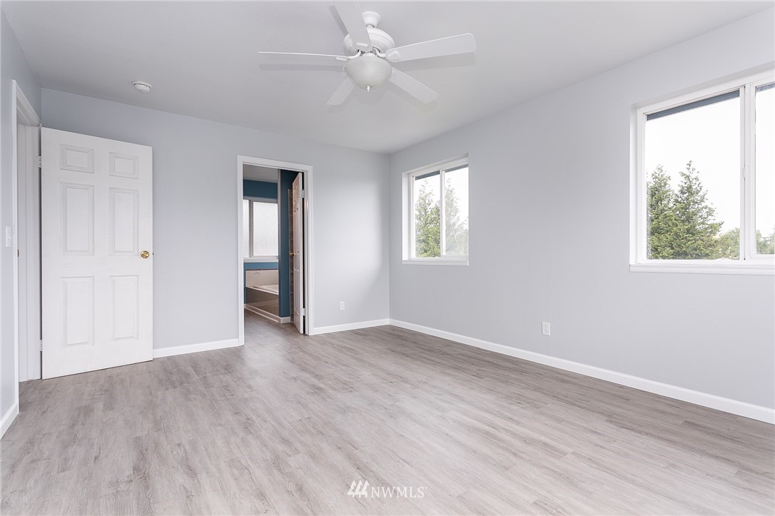 2419 East Badger Road Everson, WA 98247 - Photo 15 of 34 an empty room with wooden floor ceiling fan and windows