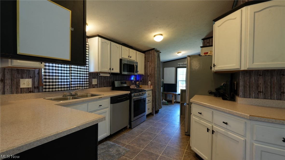 70871 Angus Road Cambridge, OH 43725 - Photo 16 of 29 Kitchen featuring dark tile floors, appliances with stainless steel finishes, white cabinets, light countertops, and vaulted ceiling