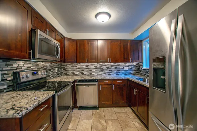 a kitchen with stainless steel appliances granite countertop a stove a sink dishwasher and a refrigerator