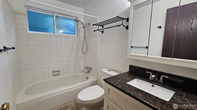 a bathroom with a granite countertop sink toilet a mirror a bathtub and shower