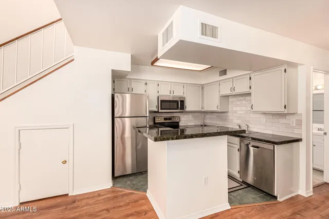 a kitchen with stainless steel appliances granite countertop a refrigerator and a stove top oven