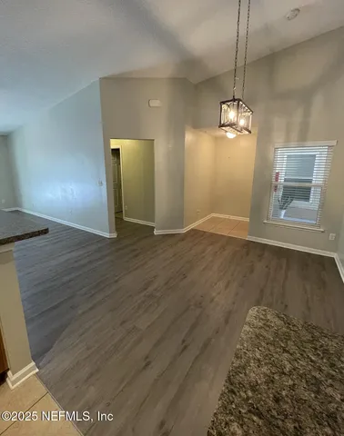 an empty room with wooden floor chandelier and windows