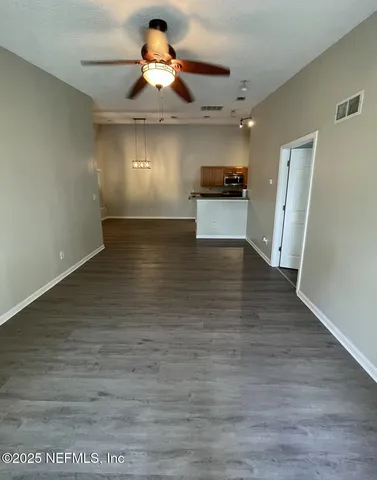 a view of a room with a ceiling fan and wooden floor