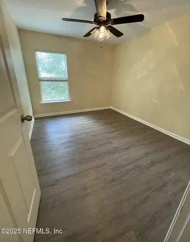 an empty room with wooden floor cabinet and windows