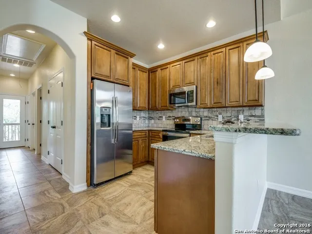 a kitchen with stainless steel appliances granite countertop a refrigerator a stove a sink and a microwave