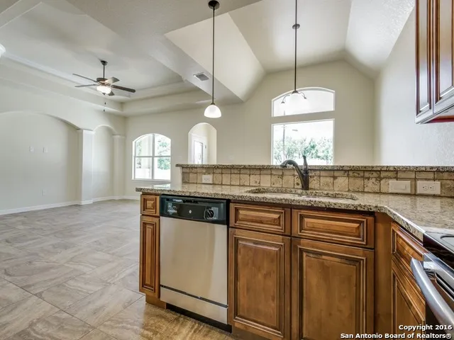 a kitchen with granite countertop a sink a counter space appliances and cabinets