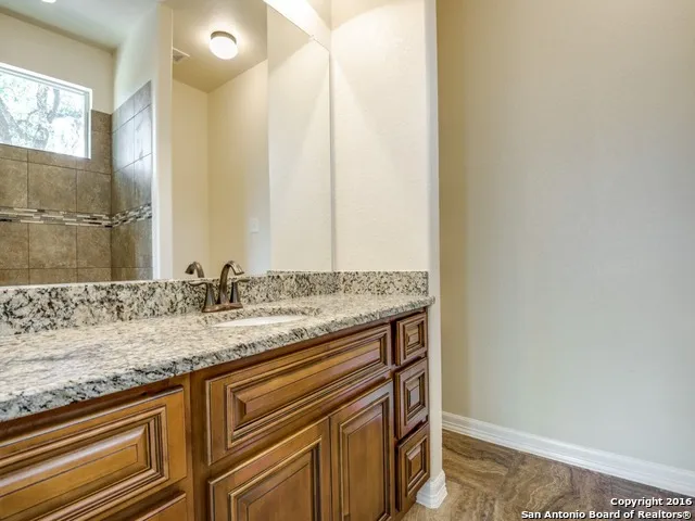 a bathroom with a granite countertop sink a mirror and shower