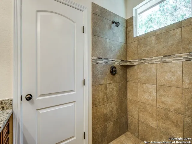 a bathroom with a granite countertop shower mirror and window