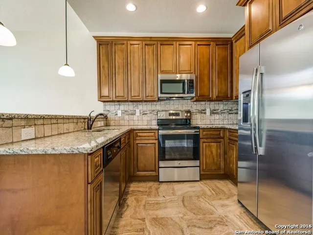 a kitchen with stainless steel appliances granite countertop a stove a sink and a microwave
