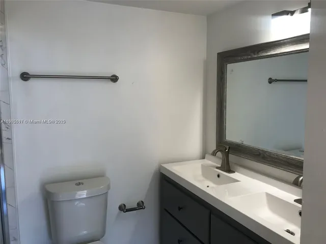 a bathroom with a granite countertop sink a toilet and a mirror