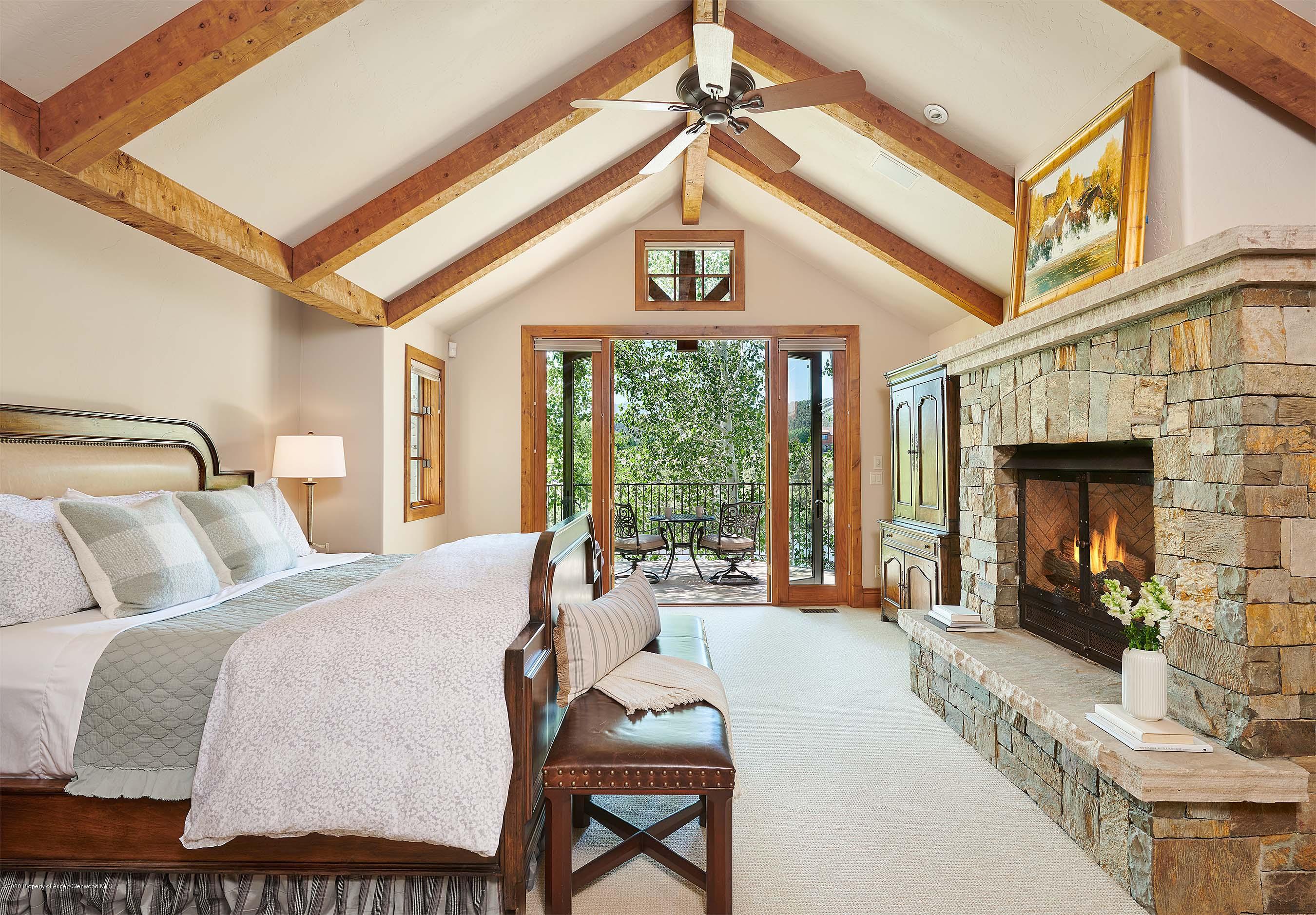 318 River's Bend Carbondale, CO 81623 - Photo 14 of 39 a bedroom with a bed a balcony a flat screen tv and a fireplace