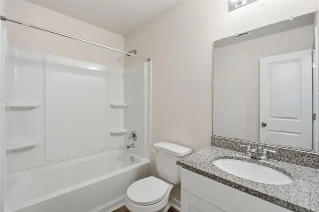 a bathroom with a granite countertop sink toilet mirror and shower