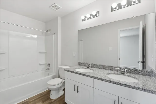 a bathroom with a granite countertop sink toilet mirror and bathtub