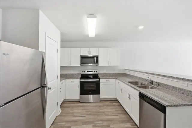 a kitchen with granite countertop a refrigerator stove and sink