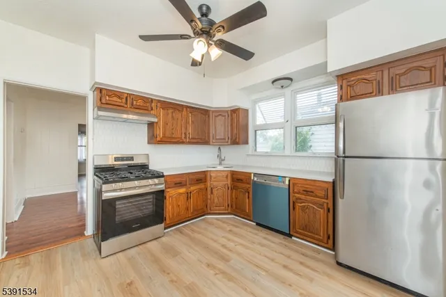 a kitchen with stainless steel appliances granite countertop a refrigerator a stove a sink and a microwave