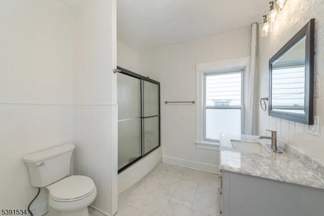 a bathroom with a granite countertop sink toilet and mirror