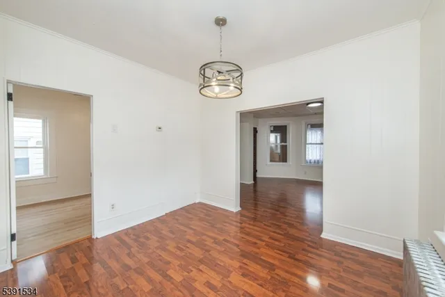a view of a room with wooden floor chandelier and windows