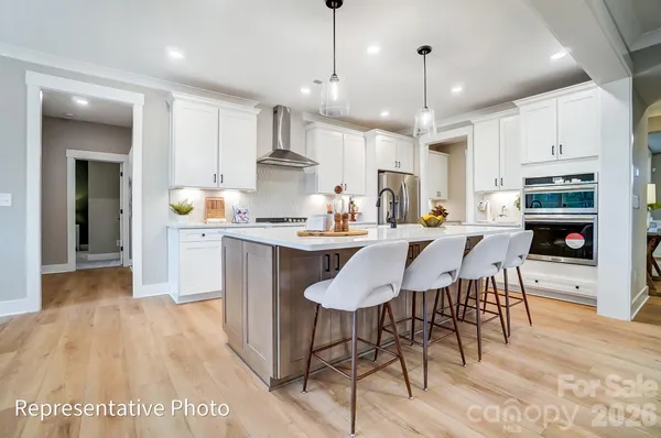 a kitchen with stainless steel appliances kitchen island granite countertop a sink a stove a dining table and chairs