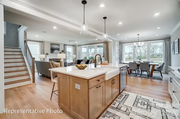 a large kitchen with kitchen island a large counter space a sink a stove and a chandelier