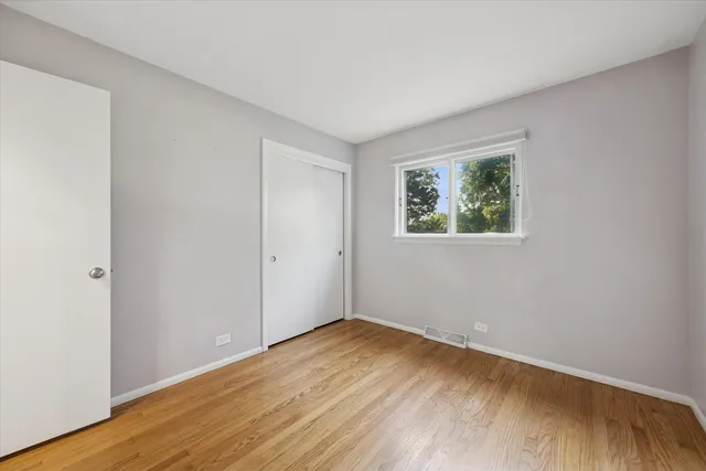an empty room with wooden floor and window