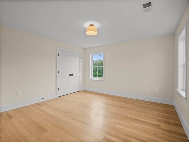a view of empty room with wooden floor and window