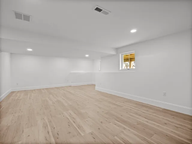 a view of an empty room with a window and wooden floor