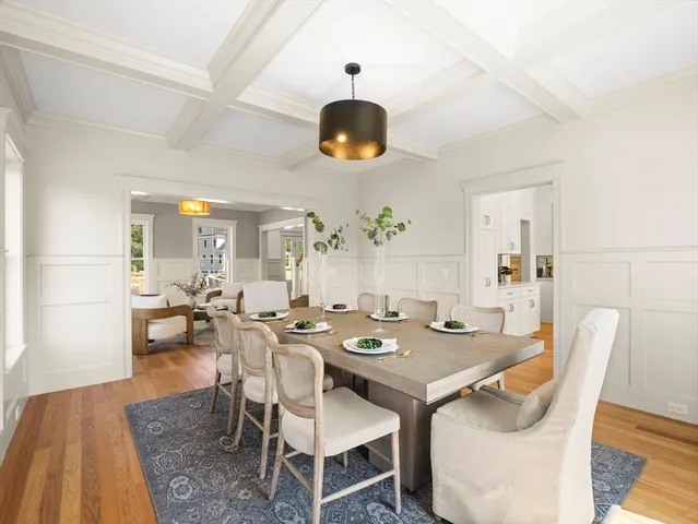a dining room with wooden floor a chandelier fan a wooden table and chairs