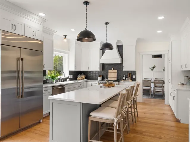 a kitchen with stainless steel appliances granite countertop a sink a stove a refrigerator and island with wooden floor