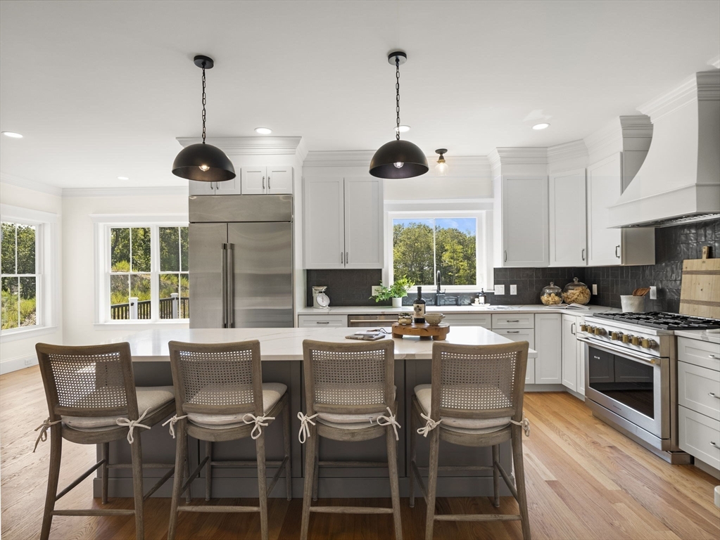 Lot 7 Weeping Willow Drive Andover, MA 01810 - Photo 9 of 42 a kitchen with stainless steel appliances granite countertop a stove top oven a sink a dining table and chairs with wooden floor